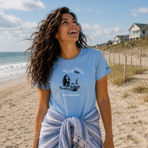 Beautiful woman wearing t-shirt from Boondrift that reads "Messy Hair on Pretty Days". Both the woman wearing the shirt and the woman on the shirt have a frisbee flying overhead.