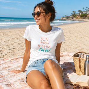 Beautiful Asian woman wearing shirt from Boondrift that reads "SUN, SAND, WATER, I'm in!" while lounging on the beach.