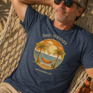 Man in 50's wearing shirt from Boondrift that reads "Beer, Hammock, and Somewhere Hot" and features a sketched beach scene. Man is relaxing in a hammock.